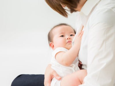 Baby being held by a woman. This post reviews how to induce lactation without pregnancy.