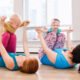 Group of two young women with children doing workout in gym class to loose baby weight. Child-friendly fitness for mothers with kids. Lifestyle concept of family activity for moms.