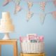 Basket with baby shower gifts and tasty cake on stools indoors