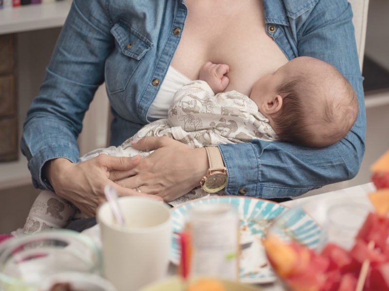 Mother breastfeeding her newborn baby girl during the lunch - breastfeeding on demand - instagram style effect applied