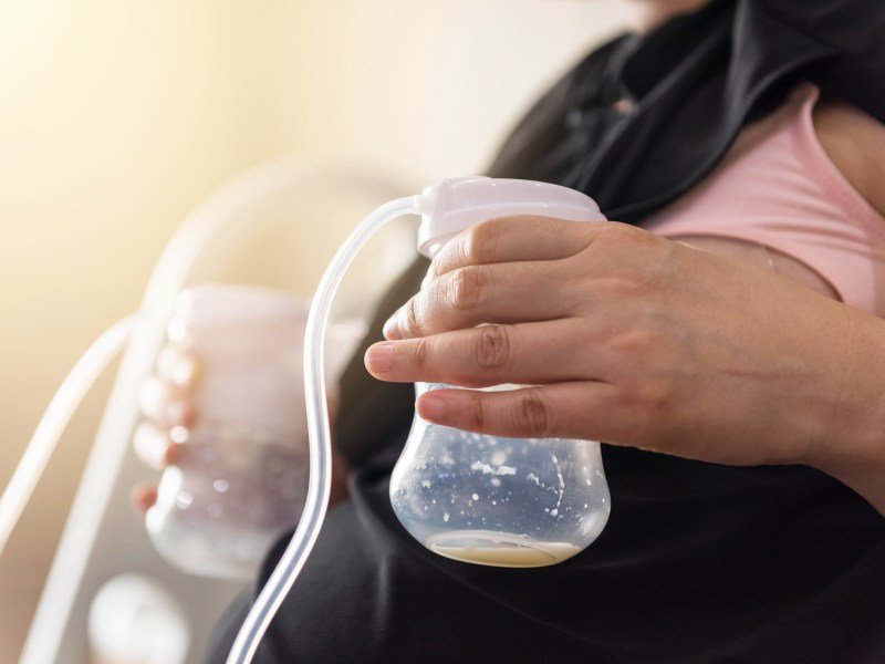 A mom pumping breast milk from both breasts. This article discusses how to use cluster pumping to increase milk supply.