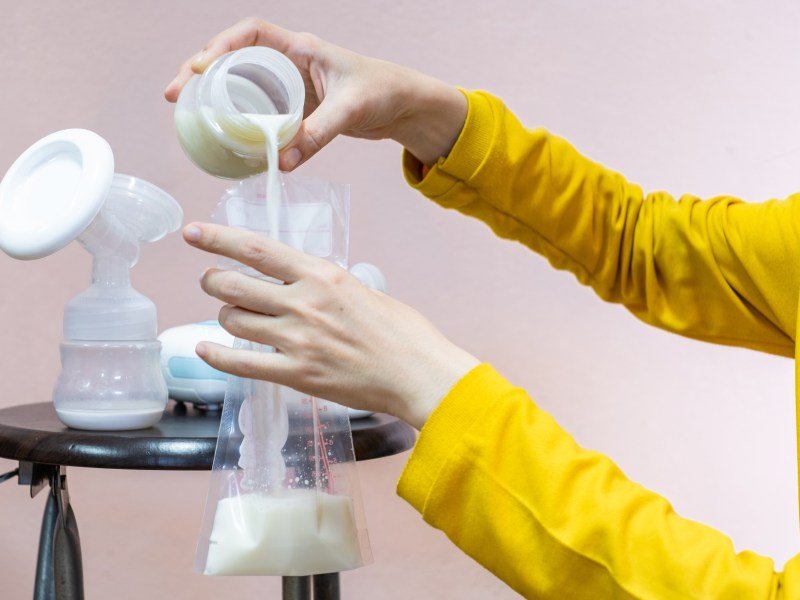 Person pouring breast milk from a bottle to a bag. This article answers the question: can you reheat breast milk?