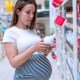 Pregnant woman in store looking at label on shampoo bottle. This article discusses the best pregnancy safe shampoos and conditioners.