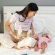 Mom sitting on bed next to baby and pumping breast milk. This article discusses sample breastfeeding and pumping schedules for newborns.